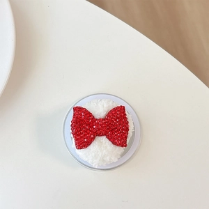Detail of white plush phone grip with a sparkling red rhinestone bow ornament