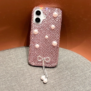 Détail de coque iPhone rose luxe avec strass, nœud perlé et pendentifs scintillants