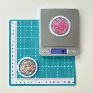 Macro detail of colorful heart sequins in a clear round case weighing 19.5g for DIY crafts