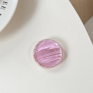 Close-up of circular pink resin phone grip with glitter and fine wave texture detail