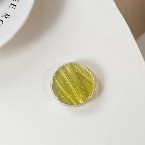 Detail of round olive green resin phone grip with elegant gold leaf glitter flakes
