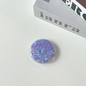 Close-up of a round Griptok featuring purple and blue heart-shaped glitter sequins