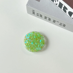 Detail shot of a round phone grip featuring green heart-shaped holographic sequins inside