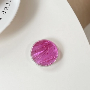 Detail of round magenta resin phone grip with elegant gold foil flakes decoration