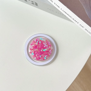 Macro view of a round Griptok featuring pink heart sequins and a holographic finish