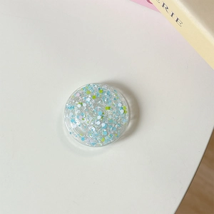 Vue macro d'un support de téléphone rond en résine avec des paillettes bleues et vertes
