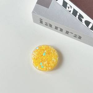 Close-up of a round phone socket stand with yellow heart sequins and holographic glitter