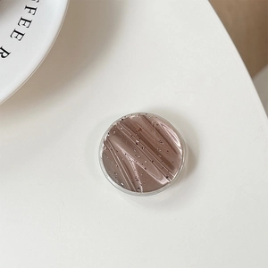 Macro detail of round coffee-brown phone grip with gold foil flakes and metallic texture