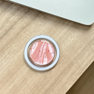 Dettaglio del supporto MagSafe con glitter rosa su una scrivania in legno chiaro