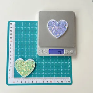 Detail view of heart-shaped glitter mirrors in purple and green with size scale