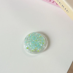 Détail macro d'un support de téléphone transparent rond avec paillettes bleu et vert