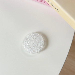 Gros plan d'un support de téléphone rond à paillettes blanches sur un bureau épuré