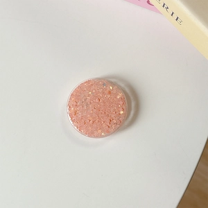 Gros plan sur un support rond à paillettes pour téléphone avec des sequins roses et oranges