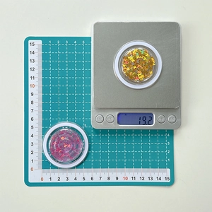 Macro shot of butterfly and star laser sequins in jars on a digital scale for size view