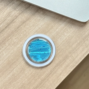 Dettaglio macro del supporto MagSafe tondo con trama a onde blu e glitter scintillanti