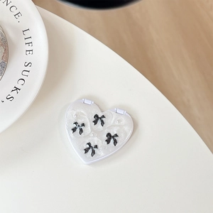 Macro shot of heart-shaped glitter makeup mirror with black bows and pearl accents