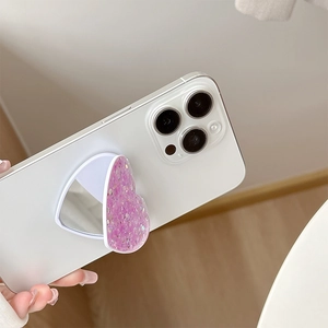 Pink heart-shaped glitter phone stand and mirror showing foldable design on white smartphone