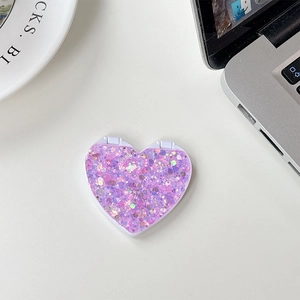 Detail of purple glitter heart-shaped folding mirror stand on a white desk workspace