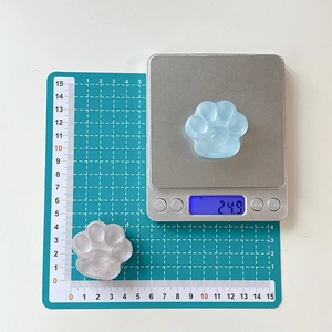 Detail shot of a 3D cat paw phone grip showing weight and scale for size reference