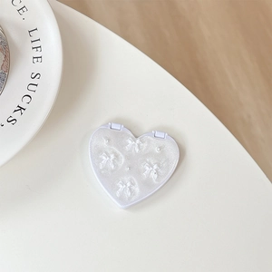 Detailed view of white heart-shaped folding mirror with glitter coating and mini bows