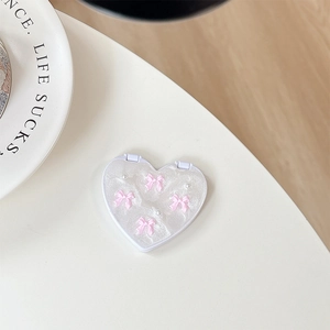 Macro shot of heart-shaped glitter makeup mirror with pink bows and pearl accents