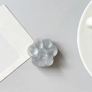 Detail of a translucent cat paw phone grip with heart relief on a minimalist desk