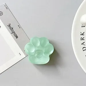 Detailed view of mint green cat paw phone grip with heart relief and frosted finish