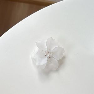 Vue macro d'un support floral blanc translucide avec pétales dépolis et perle centrale