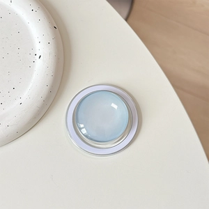Top view of a translucent blue round MagSafe phone grip on a minimalist ceramic tray