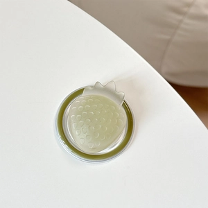 Top view of 3D translucent green strawberry magnetic MagSafe phone grip on white surface