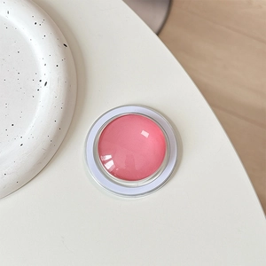 Detailed top view of a pink crystal glass MagSafe phone grip on a white minimalist desk
