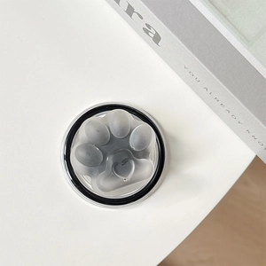 Detailed view of gray semi-transparent cat paw magnetic phone socket on a white desk