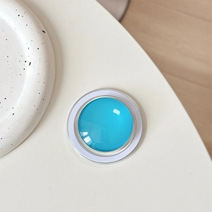 Macro shot of sky blue crystal glass magnetic phone grip with a white minimalist base