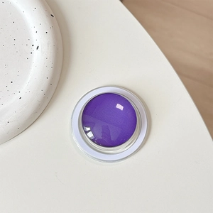 Close-up of a glossy purple MagSafe phone grip on a white minimalist desk setting