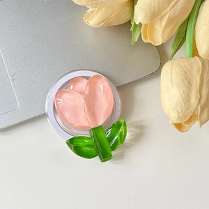 Détail du support de téléphone tulipe en résine rose avec tige verte sur bureau blanc