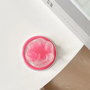 Close-up of pink translucent cat paw phone stand with a heart motif on a white surface