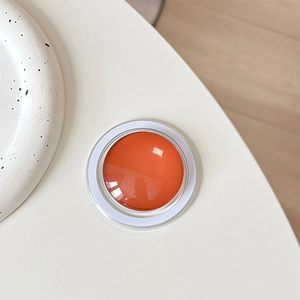 Close-up of orange magnetic phone grip with transparent dome on minimalist background