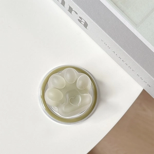 Macro shot of a matte green cat paw foldable phone socket with a heart-shaped detail