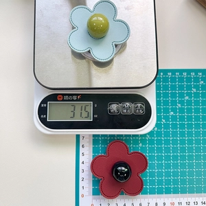 Detail showing flower phone grip diameter on cutting mat and weight on scale