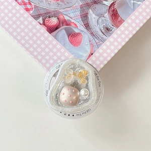 Detail of a sweet resin heart phone grip with pearl and bow on a gift display base