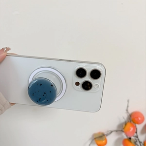 Hand holding a dark blue speckled magnetic phone socket on a white smartphone