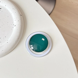 Macro shot of dark green magnetic crystal glass phone grip with white minimalist border