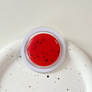 Macro view of a watermelon-style red glitter balm in a transparent circular MagSafe holder