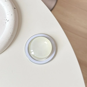 Close-up of a minimalist round crystal glass MagSafe phone grip with smooth dome finish