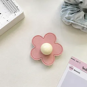 Detail view of pink leather flower phone grip with central cream bead and fine stitching