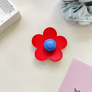Detail of red leather flower phone grip with blue bead center and neat stitching