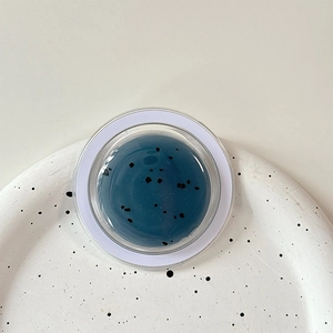 Detail view of round MagSafe phone stand with dark blue glitter and black speckle texture