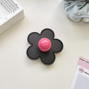 Detail of flower shaped phone grip with black leather texture and pink centerpiece