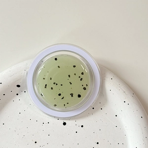 Macro detail of soothing green gel facial mask with exfoliating botanical particles