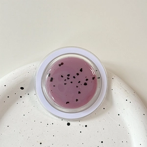 Detailed top view of purple exfoliating lip balm with fine particles in a round clear jar